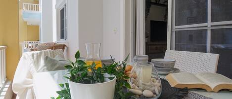 A dining area with a table set for two, featuring a book, a glass of orange juice, and a decorative centerpiece.