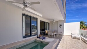 A modern outdoor pool area with a seating area, a ceiling fan, and a view of the sky. - Beautiful Brand new Beach Condo w Picuzzi (Punta Cana)