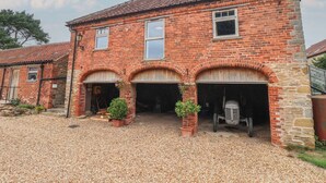 A two-story brick building with a tiled roof, two visible windows, and a gravel driveway. - The Annex at Manor Farm (York)