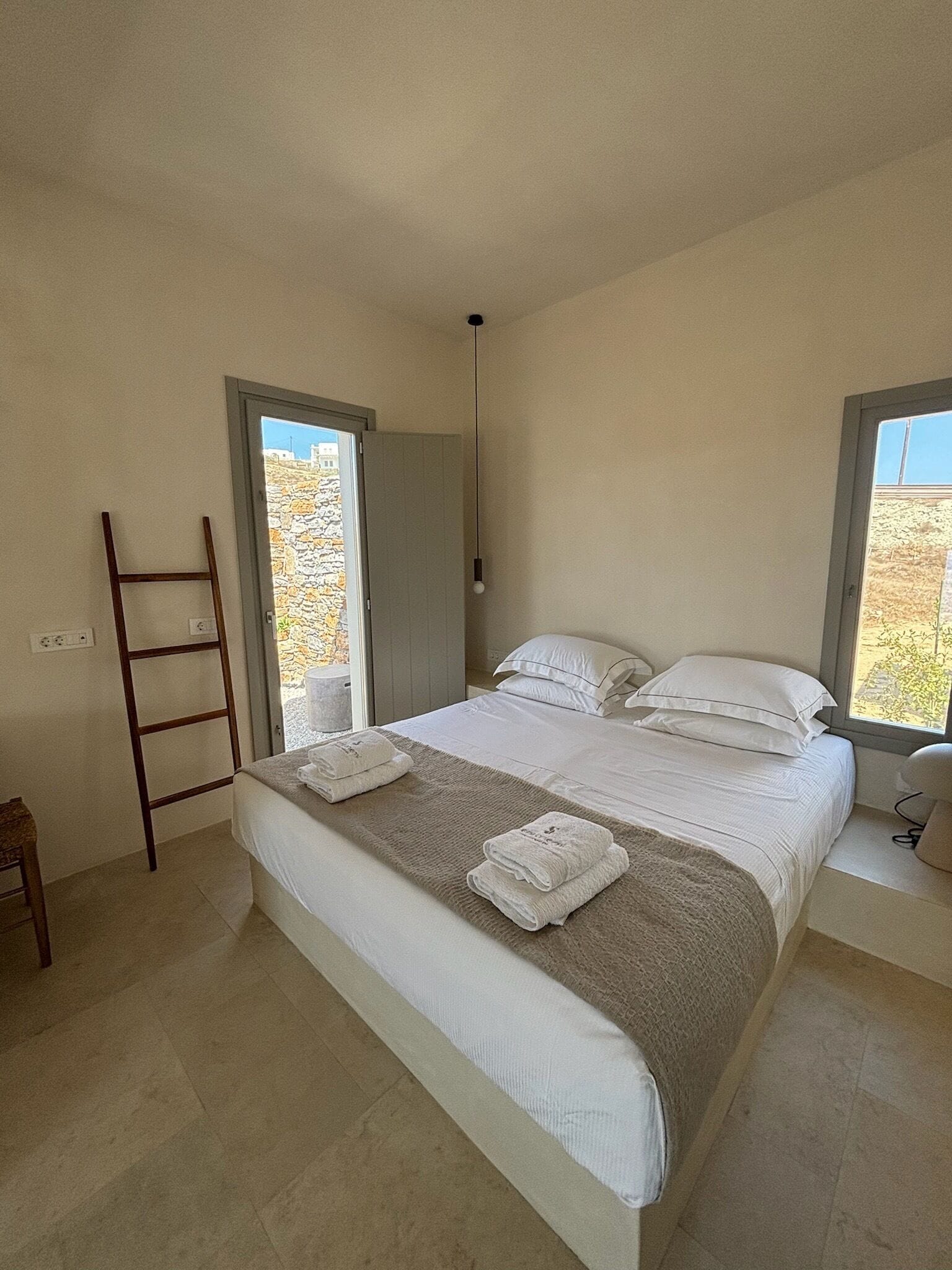 Un dormitorio con cama, una escalera y vista al exterior.