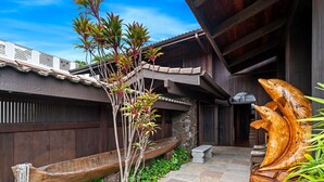 A traditional wooden building with a stone pathway, a wooden boat, and a large wooden sculpture. - Architectural Gem With Infinity Pool Ocean Views - Vrkcv (Kailua-Kona)