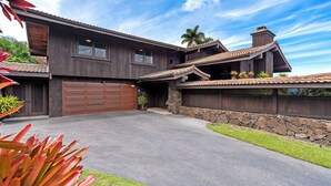 A modern two-story house with a stone facade, a large garage, and a well-maintained lawn. - Architectural Gem With Infinity Pool Ocean Views - Vrkcv (Kailua-Kona)