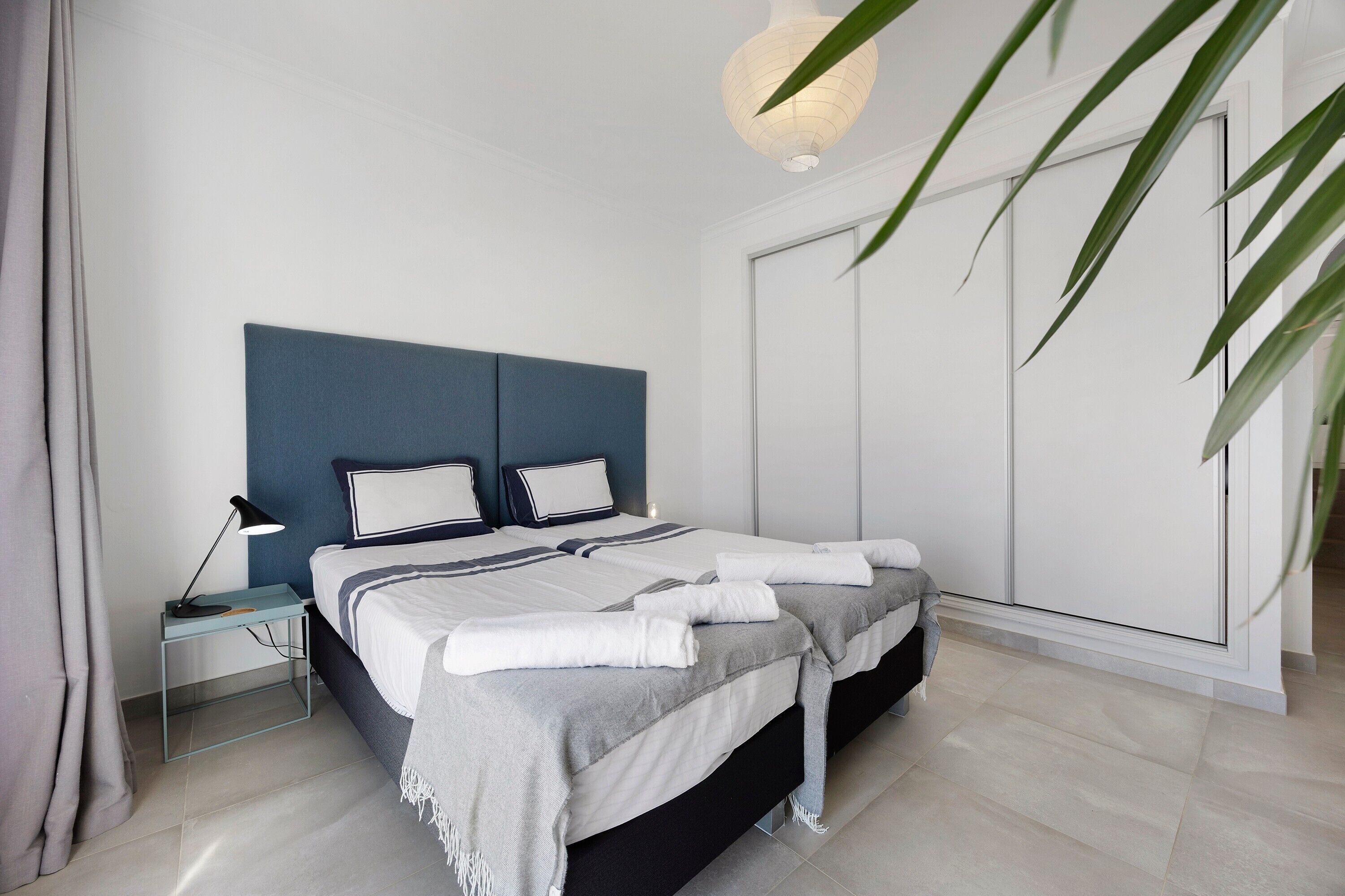 A modern bedroom with a bed, bedside tables, a lamp, and a large window.