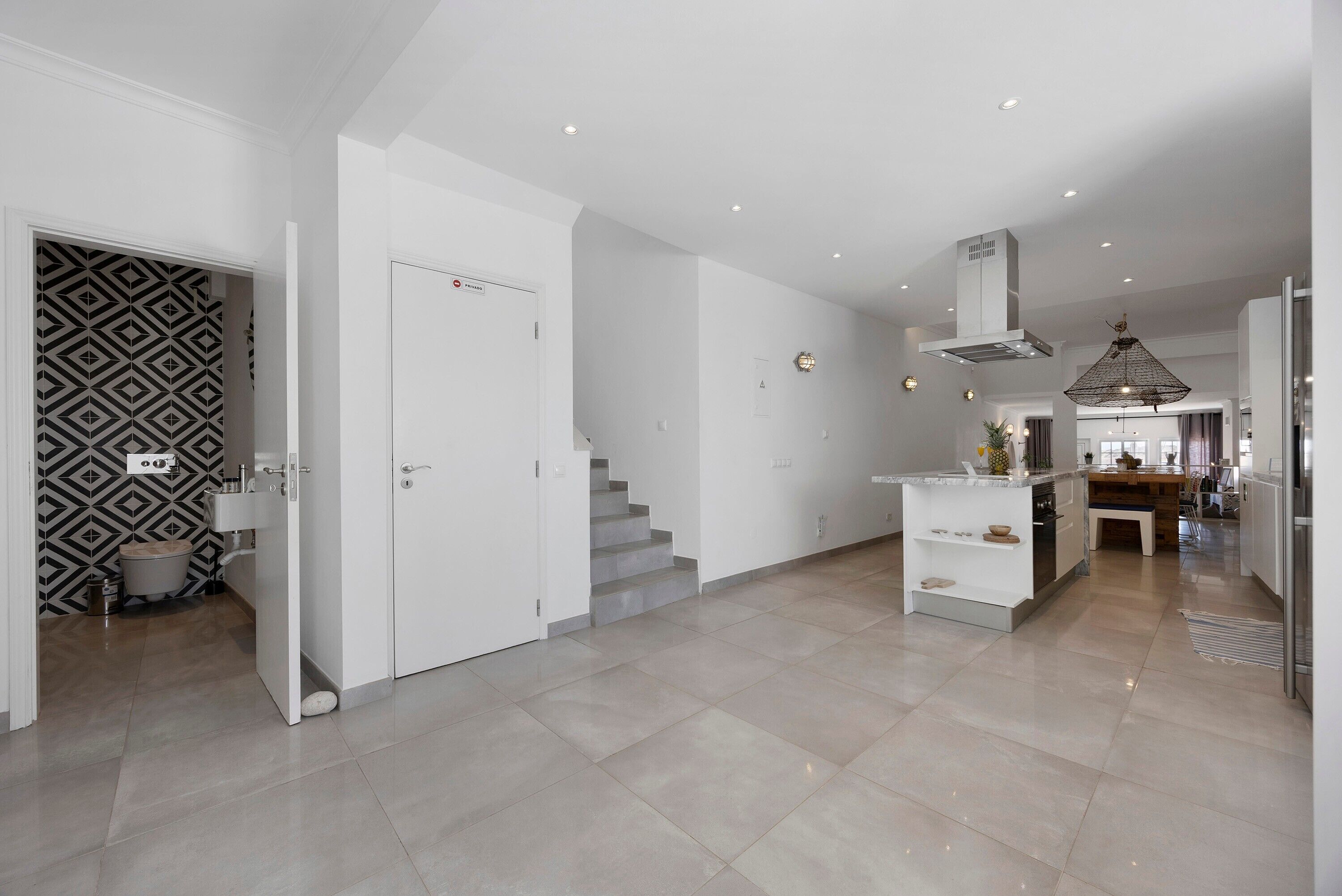 A modern kitchen with a central island, a dining area, and a staircase leading to an upper floor.