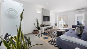 Een moderne woonkamer met een bank, televisie en decoratieve tapijten.