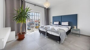 Een moderne slaapkamer met een bed, nachtkastje, potplant en uitzicht naar buiten.
