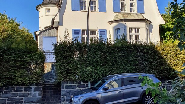 A two-story house with a garage, a driveway, and a parked car.