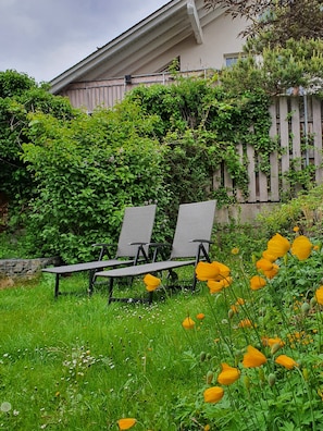 Un jardin avec une clôture en bois, un banc et une maison en arrière-plan.