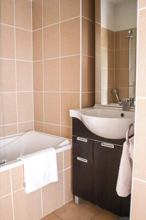 A bathroom with a bathtub, a sink, and a mirror.