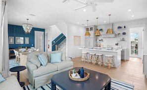 A modern living space with a sofa, coffee table, and kitchen area with bar stools.