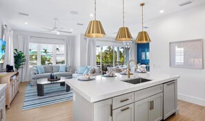 A modern kitchen with a central island, white cabinetry, and pendant lighting.