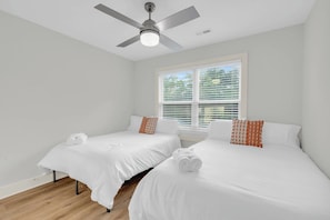 Ein Hotelzimmer mit zwei Betten, einem Deckenventilator und einem Fenster mit Jalousien.