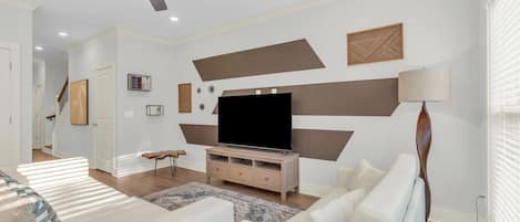 Una sala de estar moderna con un televisor de pantalla plana, un ventilador de techo y un sofá.