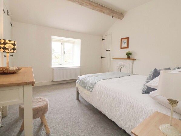 A bedroom with a bed, a desk, a chair, a window, a radiator, a fireplace, and a picture on the wall. - Isfryn (Mold)