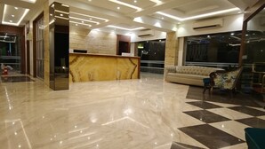 A lobby with a marble reception desk, a sofa, and a checkered floor. - MERITAS GRAND INN (Calangute)