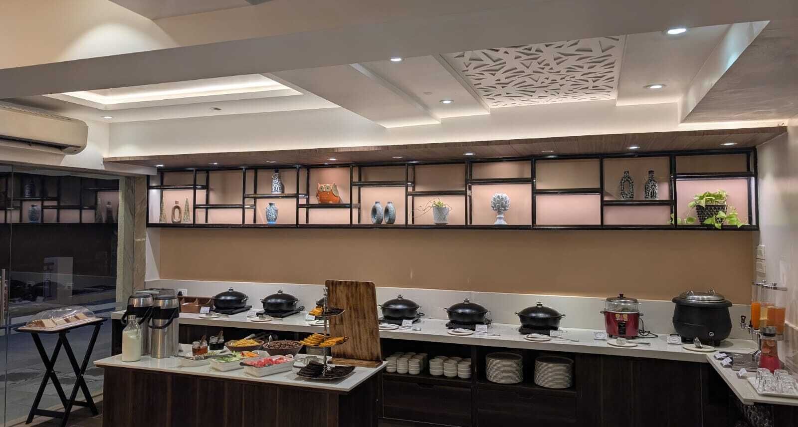 A modern kitchen with a buffet setup, including various food items and cooking equipment.