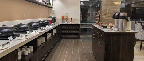 Una cucina moderna con un lungo bancone, diverse pentole da cucina e un angolo caffè.