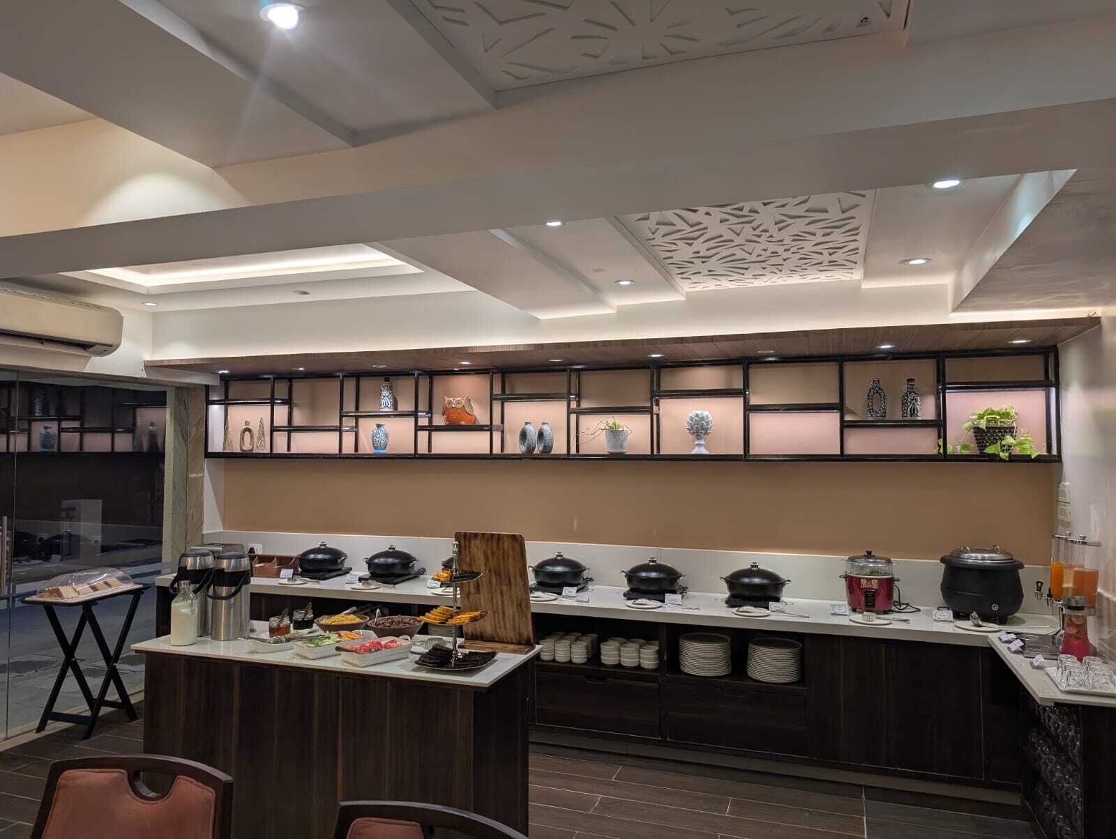 A modern kitchen with a central island, built-in shelves with decorative items, and a variety of food and drink dispensers.