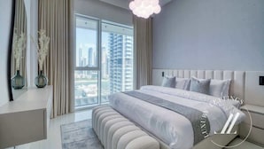 Un dormitorio moderno con una cama grande, vistas de la ciudad y una lámpara colgante.
