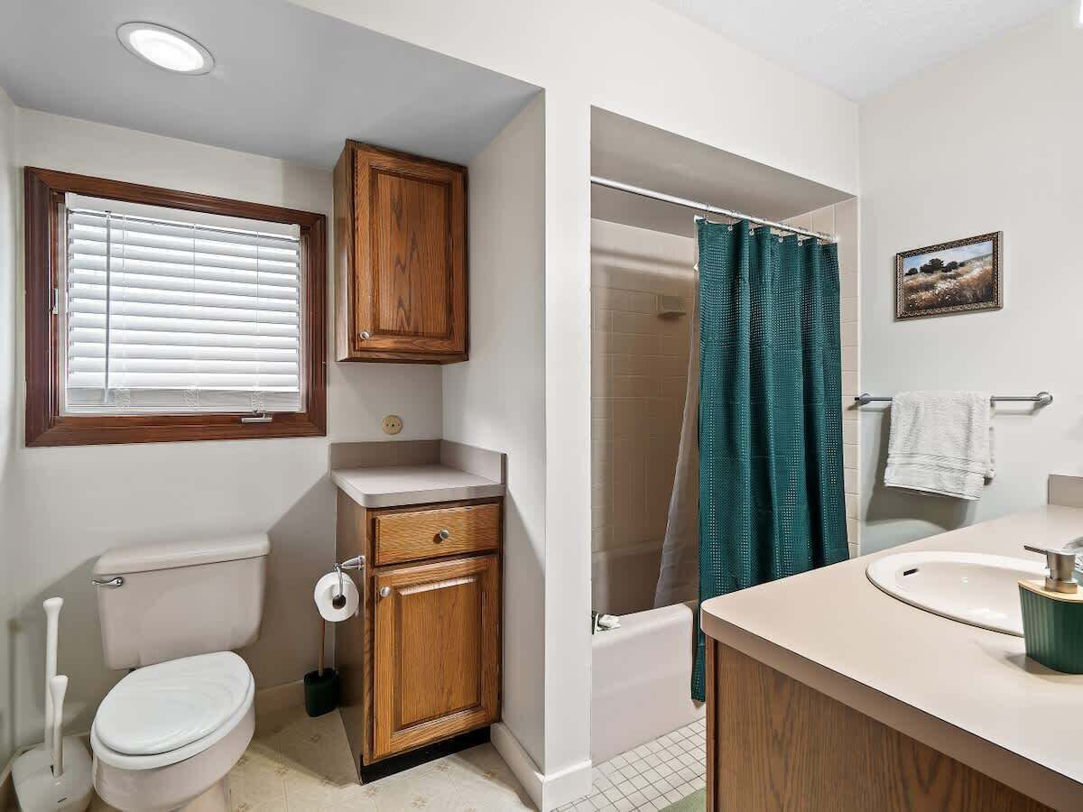 Une salle de bain équipée de toilettes, d’un meuble en bois, d’une douche et d’un lavabo.
