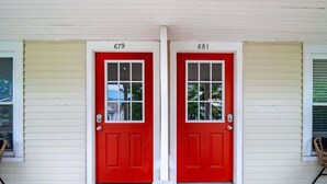 A house with two red doors labeled 679 and 681, white siding, and a front porch with a doormat that says "Stay Home Stay Safe." - Entire Duplex - Historic District - Sleeps 12 (Bedford)