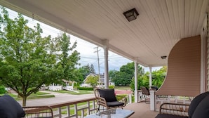 A covered porch with wicker furniture, a glass table, and a view of a residential street. - Entire Duplex - Historic District - Sleeps 12 (Bedford)