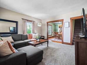 A living room with a sectional sofa, a coffee table, and a TV. There is a staircase leading to another room. - Historic District - Fully Stocked Kitchen-Sleeps 6 (Bedford)