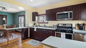 A modern kitchen with dark wooden cabinets, stainless steel appliances, and a granite countertop. - Historic District - Fully Stocked Kitchen-Sleeps 6 (Bedford)