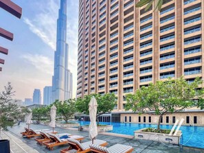 A rooftop pool area with lounge chairs and umbrellas, surrounded by high-rise buildings. - Luxurious Studio Flat with Burj Khalifa Views (Dubai)