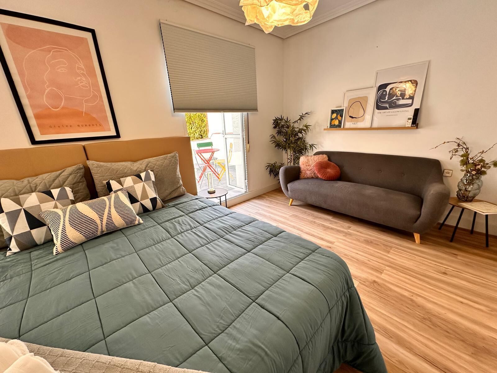 Een moderne slaapkamer met een groot bed, een grijze bank en een klein tafeltje met een vaas.
