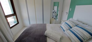A neatly made bed with a gray blanket, a white pillow, and striped pillows. - COBAR0117 - Edifício Yacht Residencial (Salvador)