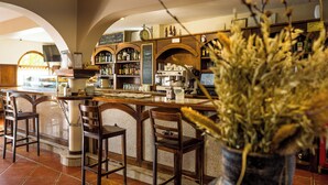 Zona de bar con sillas de madera, una barra y una variedad de botellas.