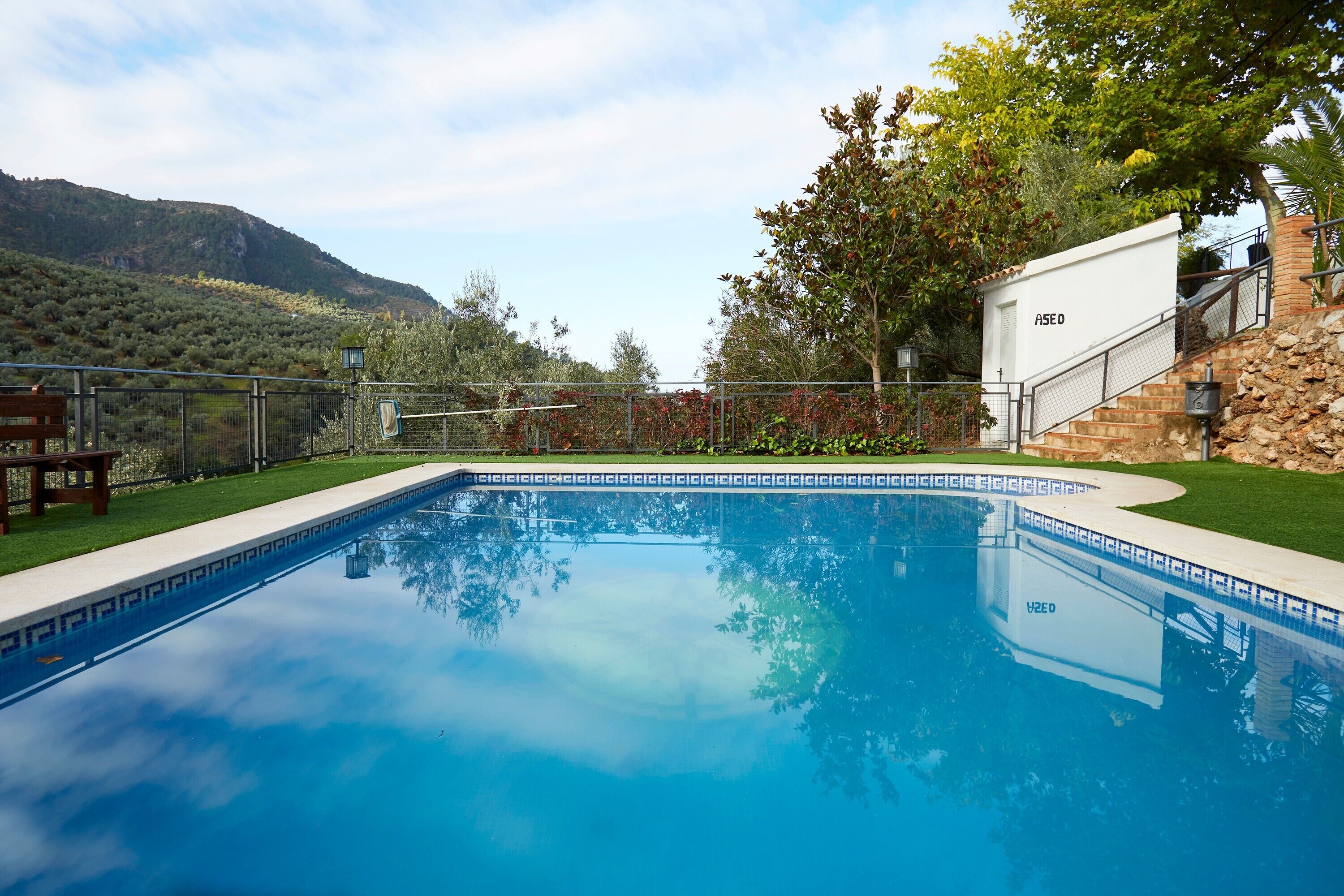 Una piscina con vistas despejadas del paisaje circundante, que incluye una ladera y árboles.