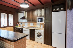 Una cocina con lavadora, microondas y refrigerador.