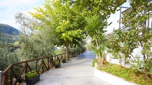 A concrete pathway flanked by greenery and a wooden fence, leading towards a mountainous landscape. - Rural House 'Fuente Los Avellanos' with Mountain View, Wi-Fi and Air Conditioning (Villanueva del Arzobispo)