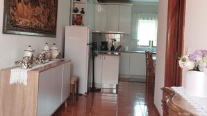 Une cuisine avec des meubles blancs, un réfrigérateur et un coin repas comprenant une table et des chaises.