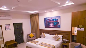 Ein Hotelzimmer mit einem großen Bett, einem Sessel, einem Schreibtisch und einem Bild an der Wand.
