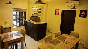Eine kompakte Küche mit Kochinsel, einem Essbereich mit Holztisch und Stühlen sowie einer Bar mit Regalen und Flaschen.