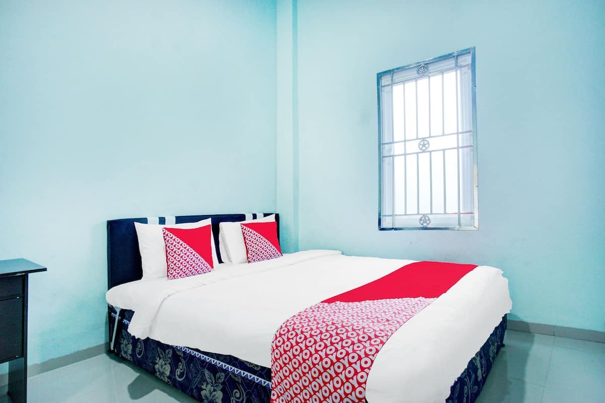 Un dormitorio con cama, una ventana con rejas y una mesita de noche.