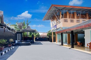 A courtyard with a covered seating area, a gate, and a building with a blue sign. - Hotel O Al Barokah Embun Kostel Syariah (Palembang)