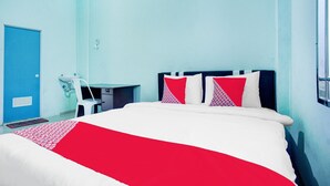 Een hotelkamer met een bed, een bureau met stoel en een raam.