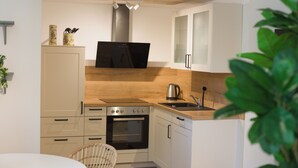 A compact kitchen with white cabinets, a built-in oven, a microwave, and a sink. - Moorrose: Holiday apartment in the Frisian Gulfhof, not barrier-free (Apen)