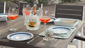 Taula de menjador a l'aire lliure amb vasos de vi, una ampolla de Prosecco i plats.