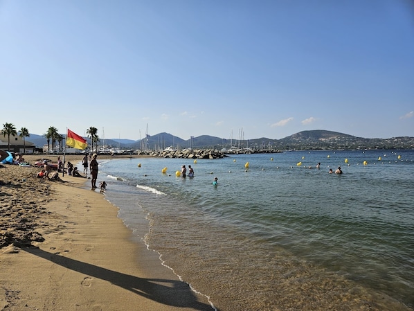 A beach with people swimming and walking along the shore, a flag, and boats in the background. - Voyage Home Mobile Home. Modern amenities at a 4-star campground (Gassin)