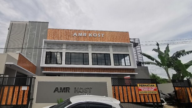 A modern building with the sign 'AMR KOST' on the facade, featuring a mix of wood and metal materials, and a gated entrance. - Hotel O Madina Homestay (Samarinda)