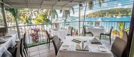 Ein Restaurant mit gedeckten Tischen mit Blick auf einen Yachthafen und Boote.