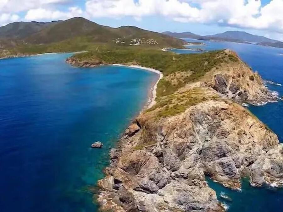 A coastal landscape with rocky terrain and clear blue waters.