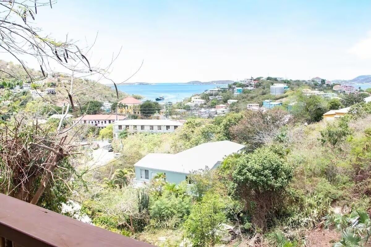 Une ville côtière dont les bâtiments sont entourés de verdure et qui offre une vue sur la mer.