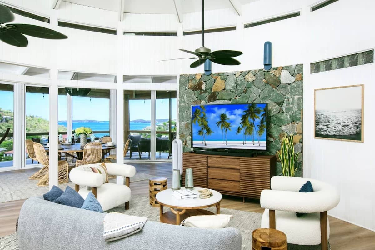 A spacious living room with a large TV, comfortable seating, and a view of the ocean.
