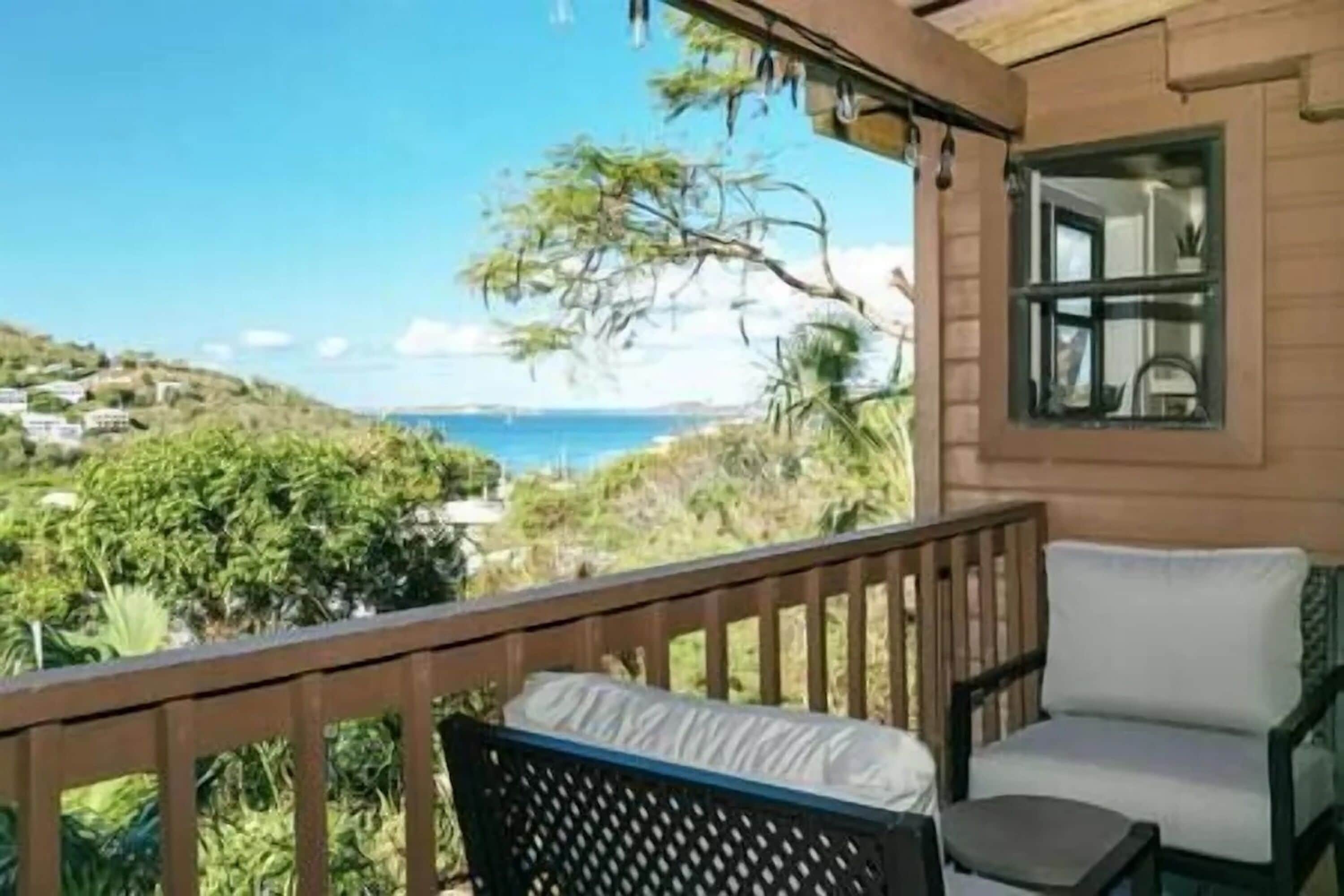 A balcony with a view of the sea, a chair, and a small table.